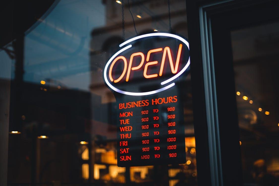 Panneau d'horaires d'ouverture affiché derrière la vitrine d'un commerce